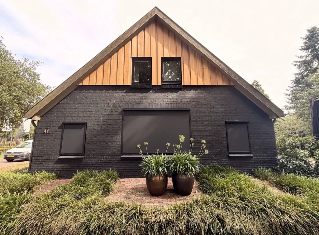 Zonnescherm boven de ramen van een woning, volledig uitgeklapt voor schaduw op het terras en bescherming tegen de zon.