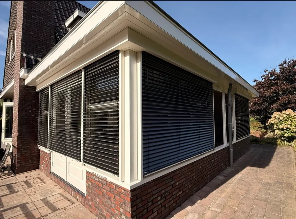 onnescherm aan de gevel van een woning, uitgeklapt om de ramen en buitenruimte te beschermen tegen direct zonlicht.